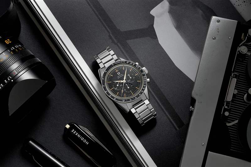 1960 年代 Omega Speedmaster Ref. 的生活方式圖片。 鋼手鏈上的 2998-6 旁邊是一本打開的書、一臺(tái)徠卡相機(jī)和一把黑色 HODINKEE 品牌的 Victorinox 瑞士軍刀。